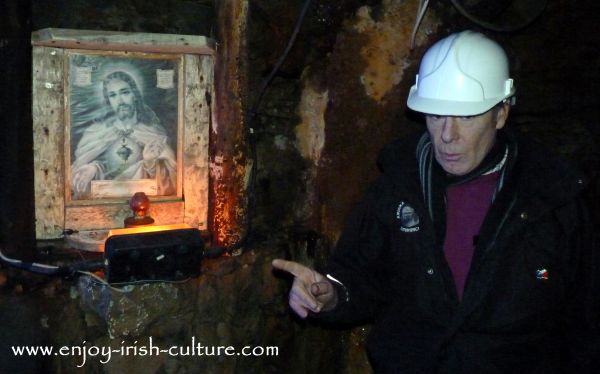 Michael the guide Mining Museum pointing at the sacred heart lamp as he talks about the importance of religion to this close knit mining community.